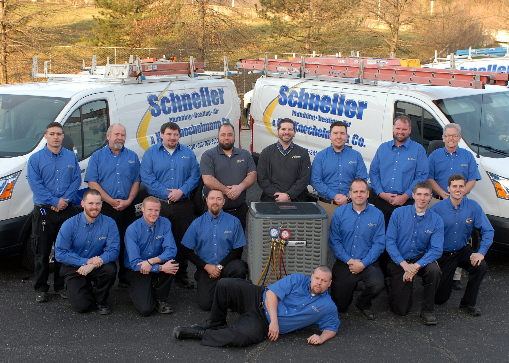 Schneller Knochelmann team standing together in front of two service vans in a parking lot.