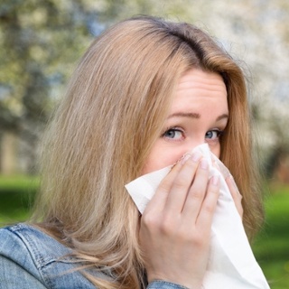 Woman looking into the camera and covering her nose with a tissue