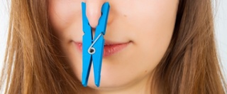 Woman with a clothespin pinching her nose.