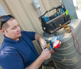 Technician reading a gauge while servicing an air conditioning unit