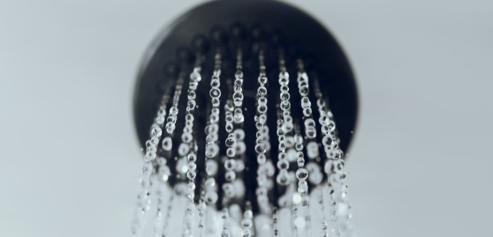 Black shower head with water on