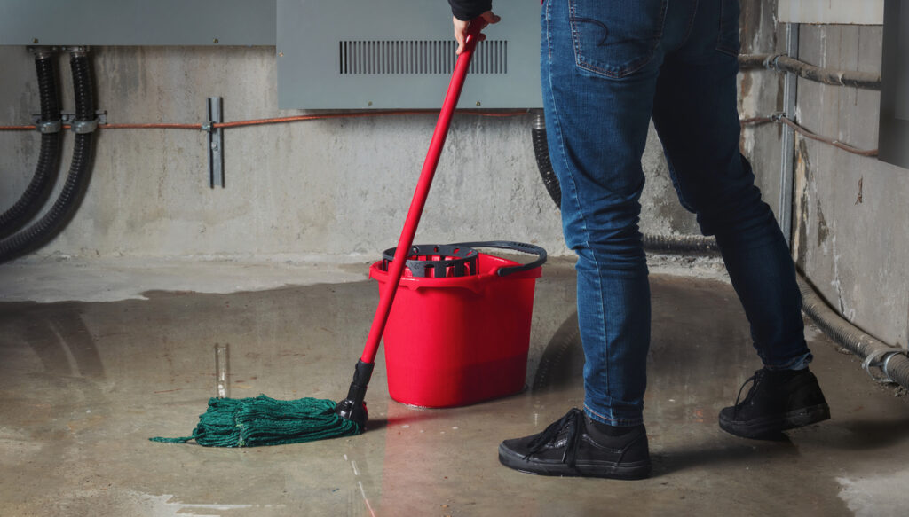 Person mopping flood from water leaks in basement or electrical room.