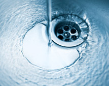 Water from sink faucet flowing down stainless steel sink drain